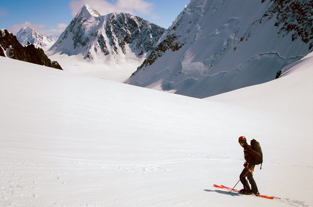 Ryan on skis looks back before ripping a big open slope in Alaska