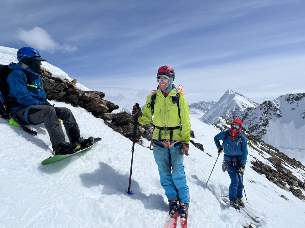 Two backcountry skiers and a splitboarder stand on top of a peak in Wrangell - St. Elias National Park