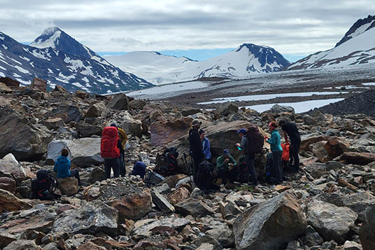 A group of backpackers take a break on rocks