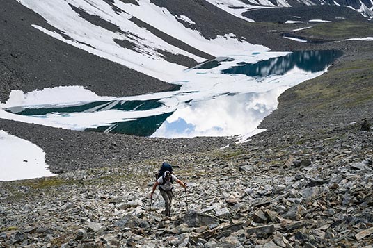 A backpacker moves uphill on a rocky slope