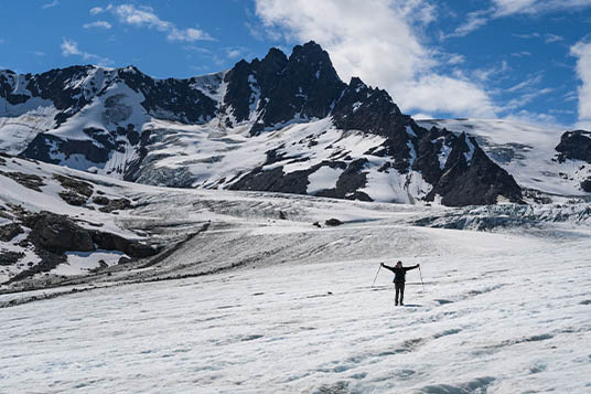 A happy hiker with arms spread on a glacier in Alaska