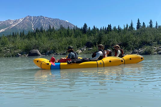 Packrafters in tandem kayaks enjoy a sunny day on calm water