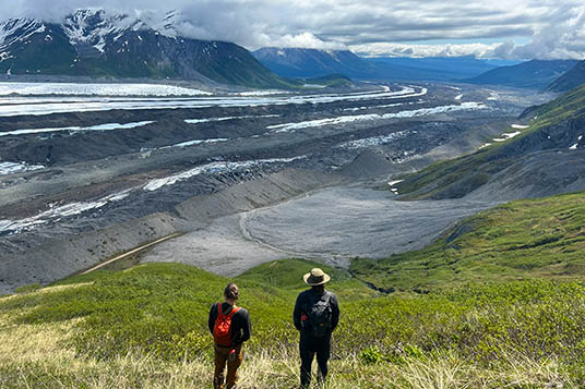 Two hikers gaze at the massive Kennicott Glacier