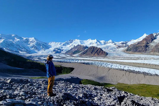 An Alaskan hiker stands in front of the Kennicott Glacier
