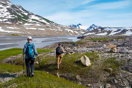 Two hikers walk along a valley in the Chugach Mountains