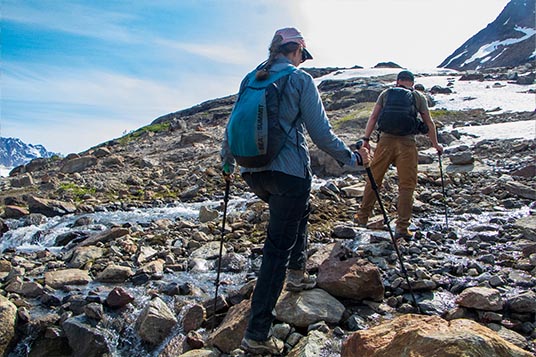 Two hikers move uphill through rocks and water