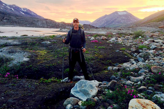 A hiker poses in the sunset at Iceberg Lake
