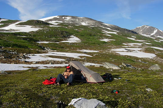 A man rests near his tent in the Alaskan backcountry