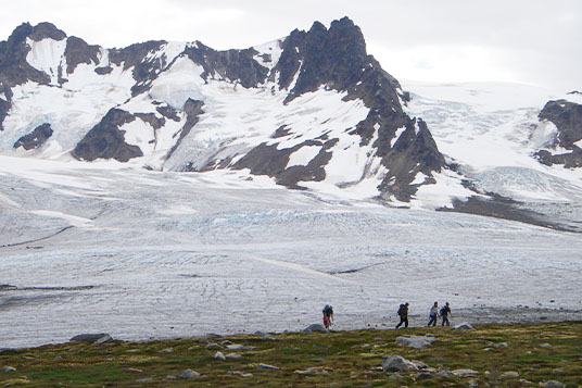 Hikers near a huge glacier in the Chugach Mountains