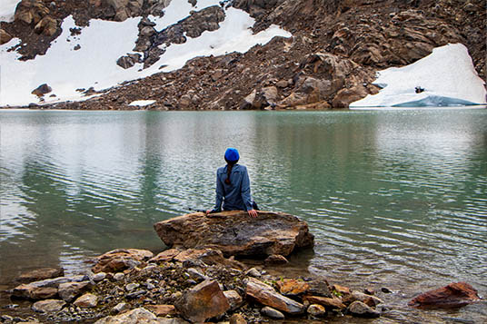Woman sitting at an alpine lake