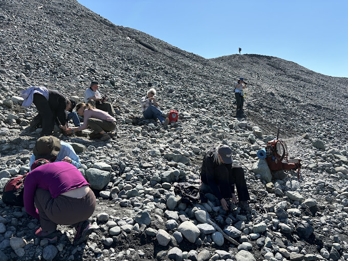Glacier hikers putting on crampons on rocky moraine