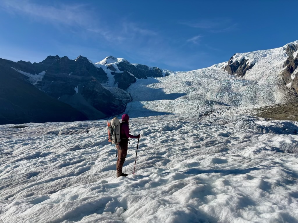 Hiker stands on glacier looking at icefall