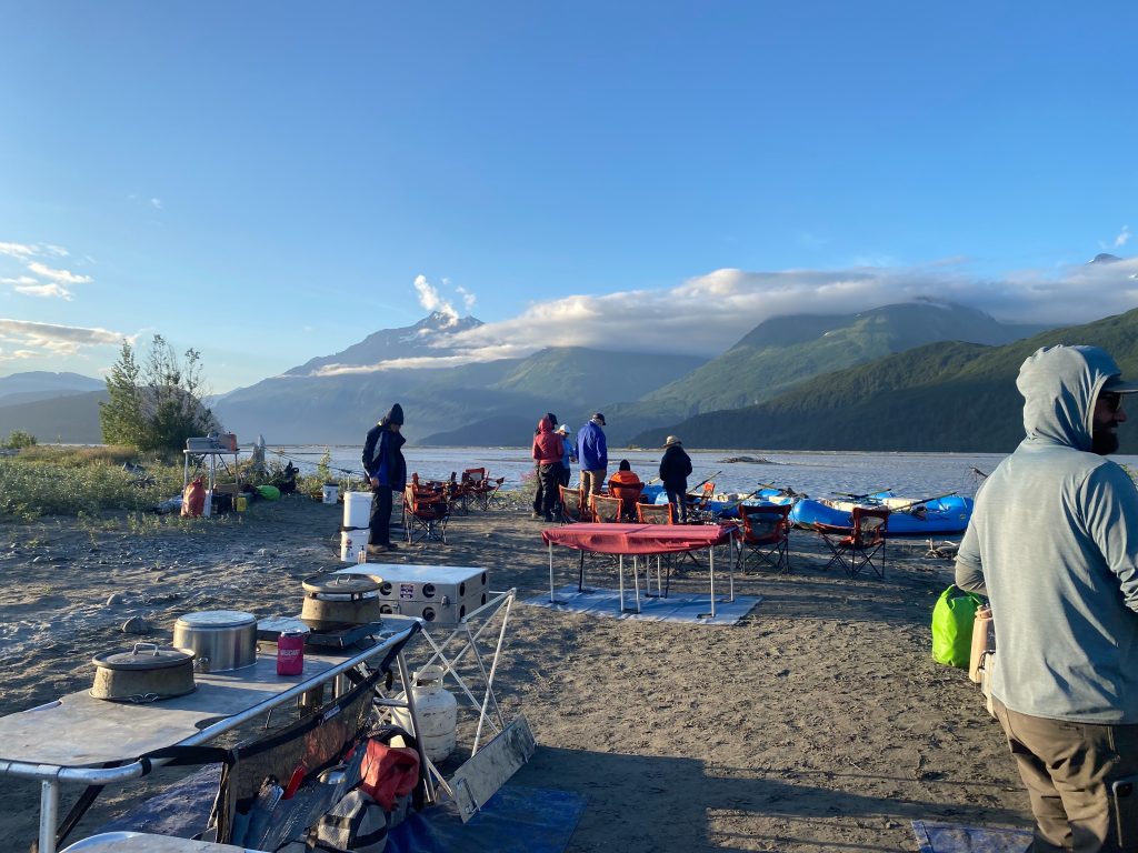 Raft guides and clients in backcountry kitchen on river bar