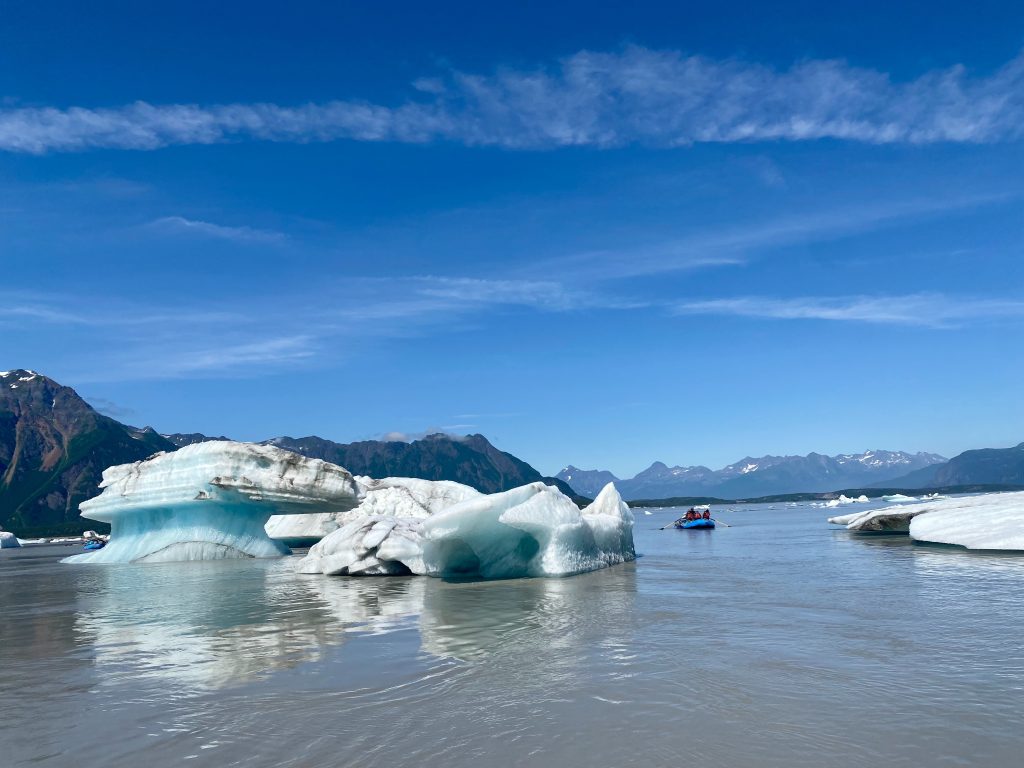 Raft floats past massive ice bergs in Copper River on Miles Lake