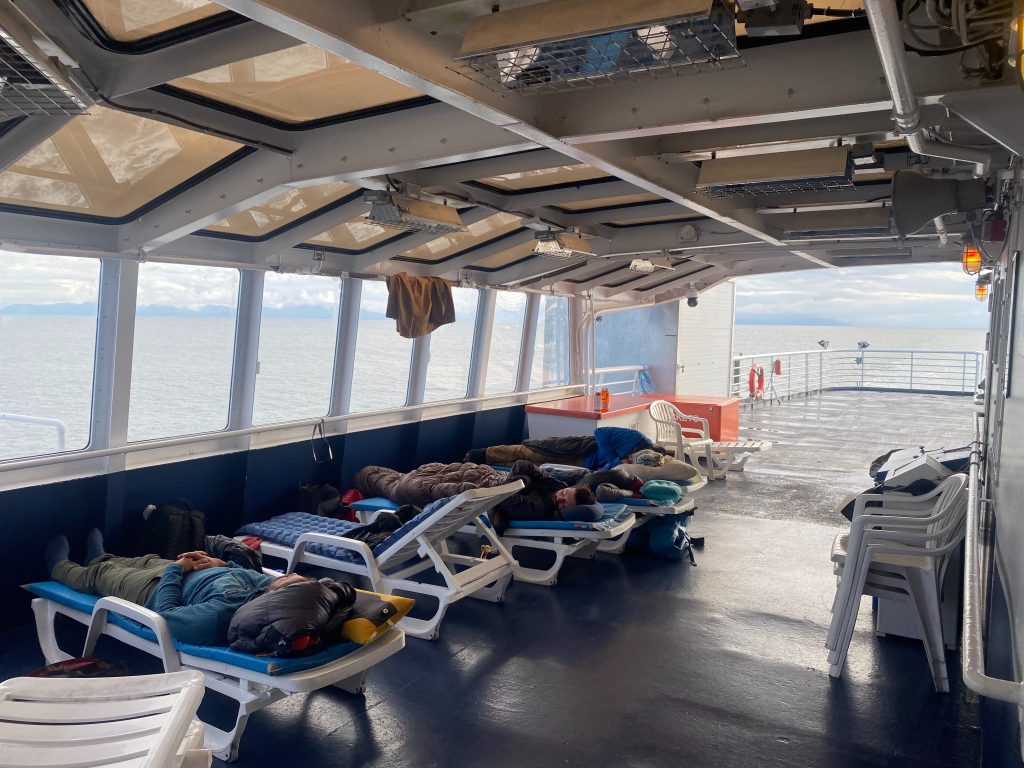 Three wilderness guides nap under the solarium on a ferry boat on the Alaska Marine Highway System